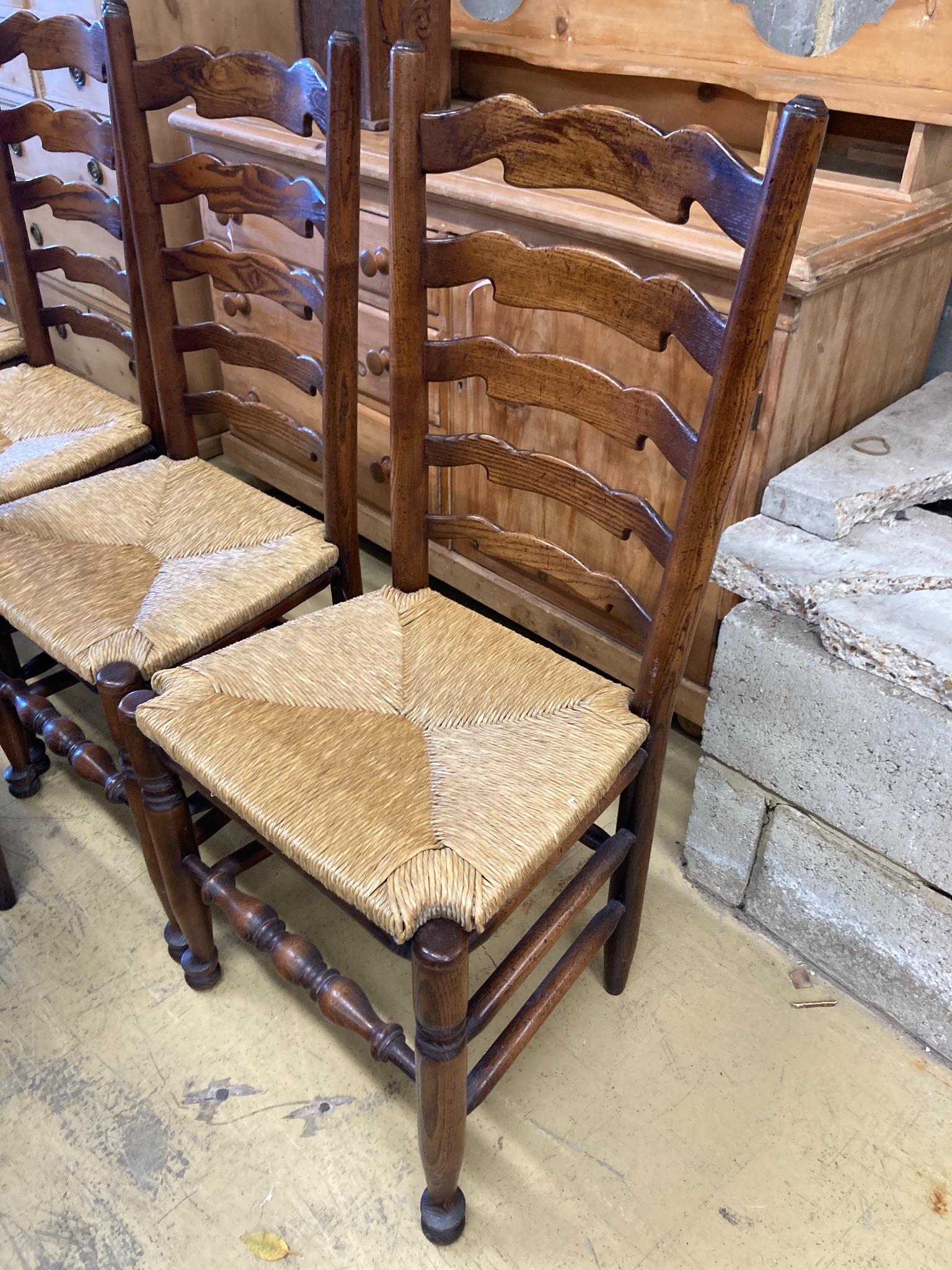 A set of five Lancashire ash and beech rush-seat ladderback chairs (one with arms)